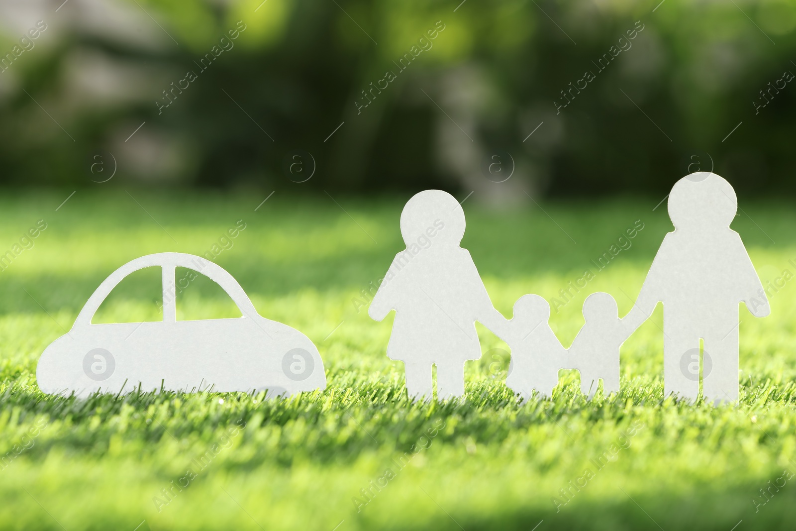 Photo of Paper cutout of family and car on fresh grass. Life insurance concept