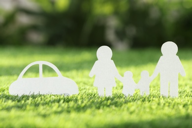 Paper cutout of family and car on fresh grass. Life insurance concept