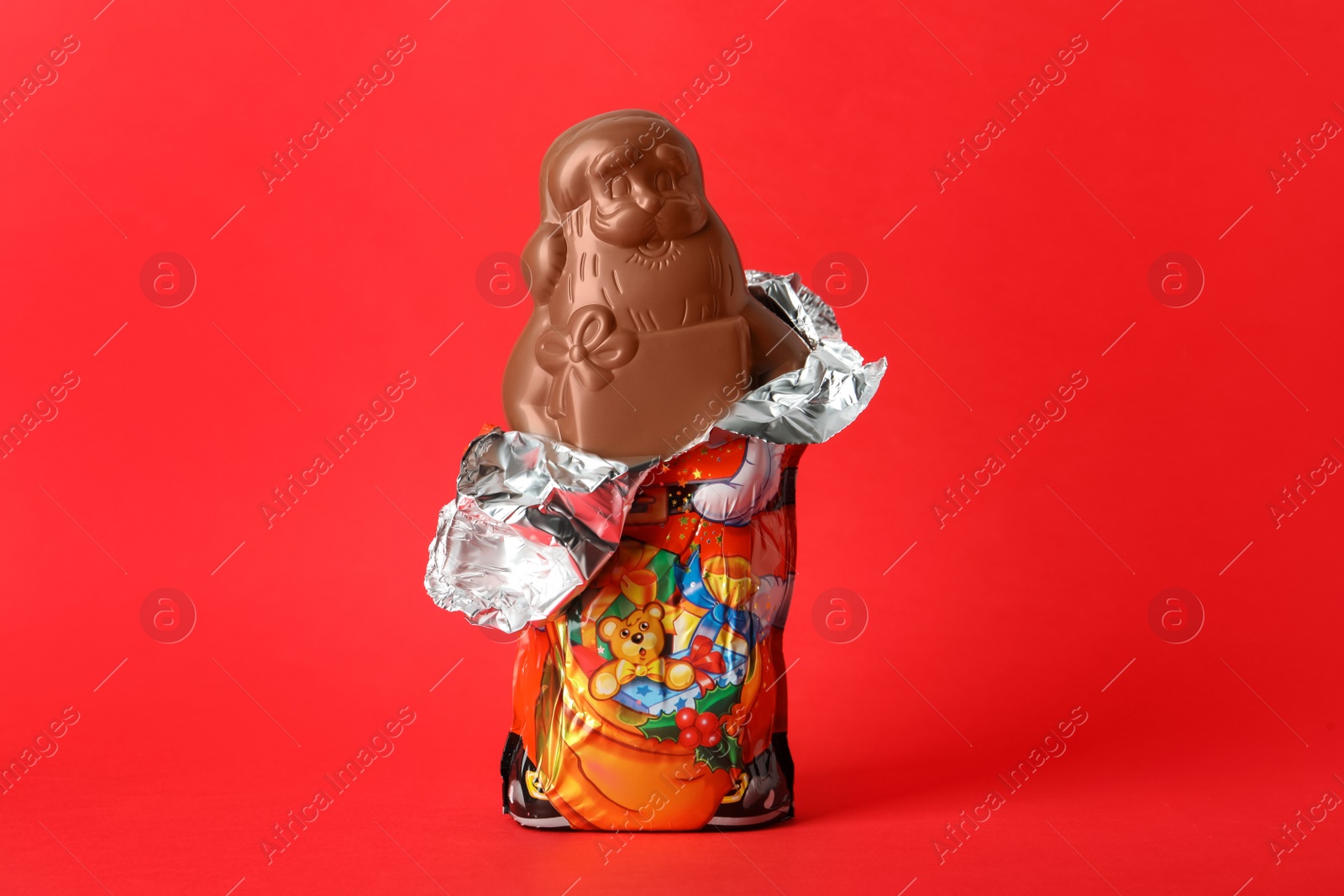 Photo of Unwrapped chocolate Santa Claus on red background