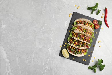 Photo of Delicious tacos with meat, vegetables and lime on light gray marble table, flat lay. Space for text