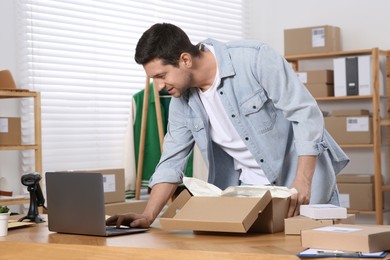 Photo of Seller with parcel and laptop working in office. Online store
