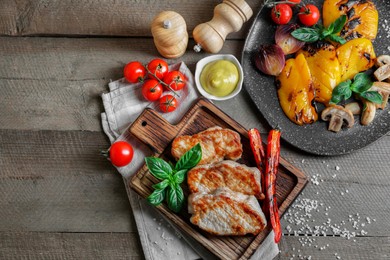 Photo of Delicious grilled meat and vegetables served on wooden table, flat lay. Space for text