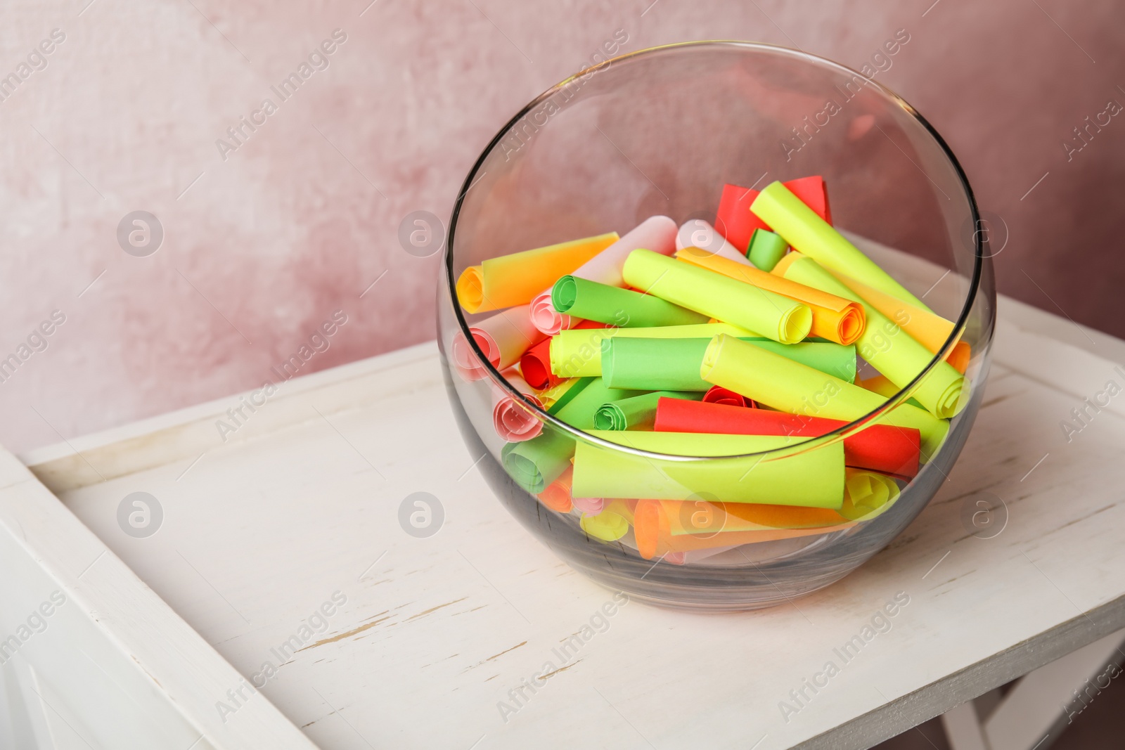 Photo of Colorful paper pieces for lottery in glass vase on wooden table. Space for text