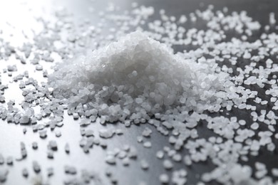 Photo of Heap of natural salt on black table, closeup