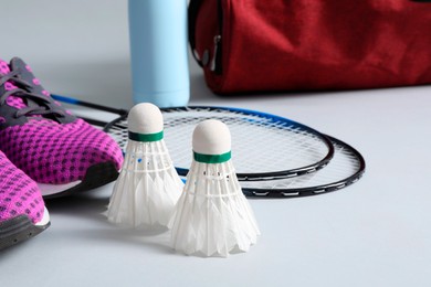 Feather badminton shuttlecocks, rackets and sneakers on gray background