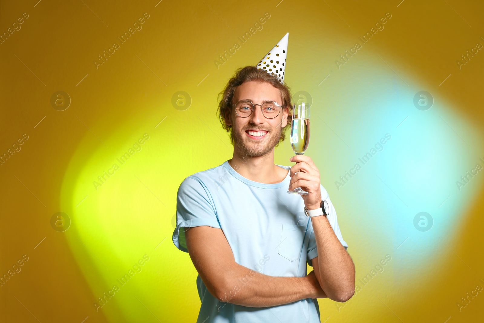 Photo of Portrait of happy man with party cap and champagne in glass on color background