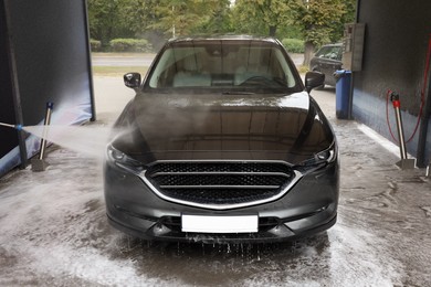 Washing auto with high pressure water jet at outdoor car wash