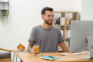 Photo of Handsome man with delicious smoothie at workplace in office. Space for text