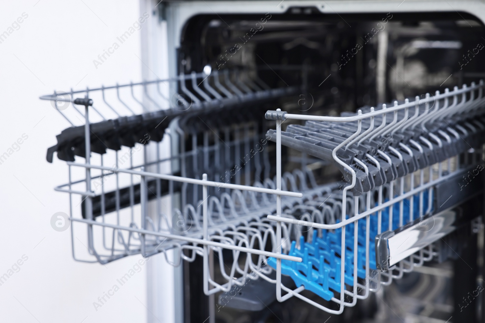 Photo of Open clean empty dishwasher indoors, closeup. Home appliance