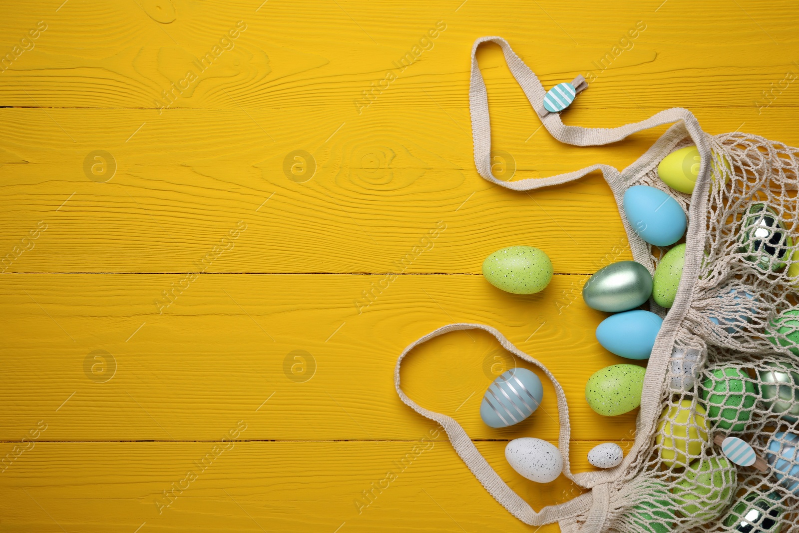 Photo of Many beautifully decorated Easter eggs on yellow wooden table, flat lay. Space for text