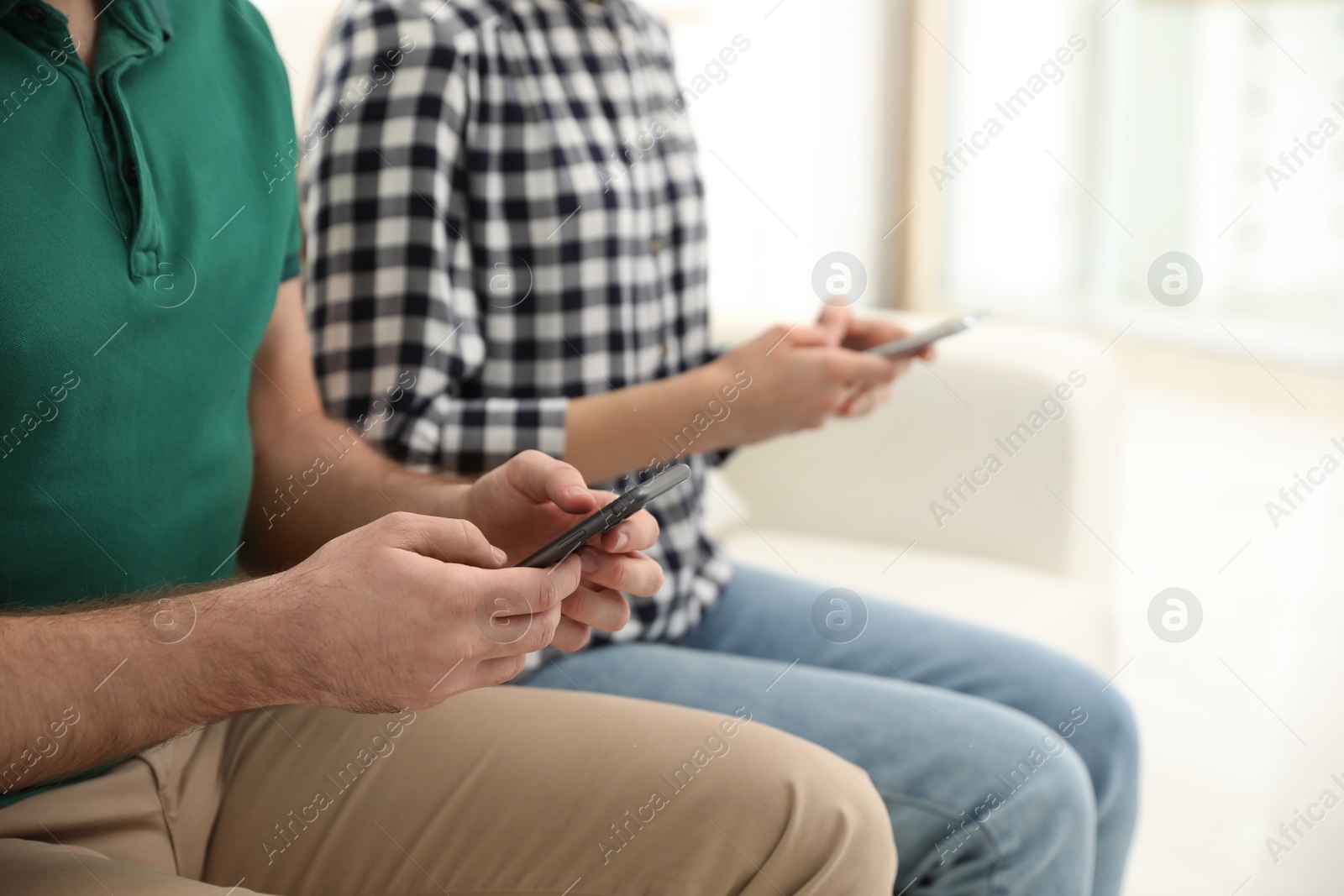 Photo of Couple addicted to smartphones at home, closeup. Relationship problems