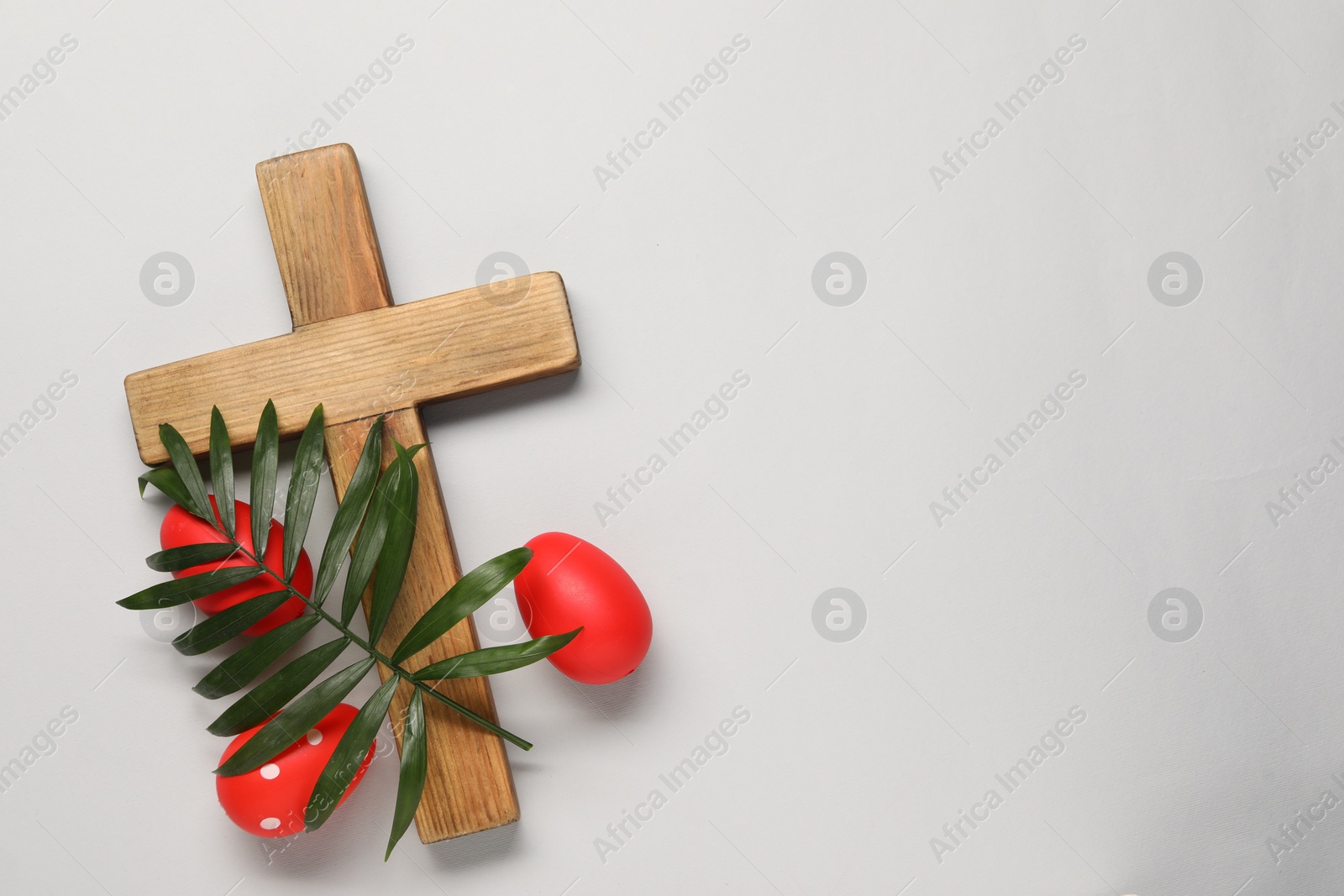 Photo of Wooden cross, painted Easter eggs and palm leaf on light grey background, flat lay. Space for text