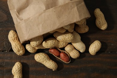 Paper bag with fresh unpeeled peanuts on wooden table, top view