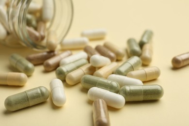 Photo of Vitamin pills and bottle on beige background, closeup