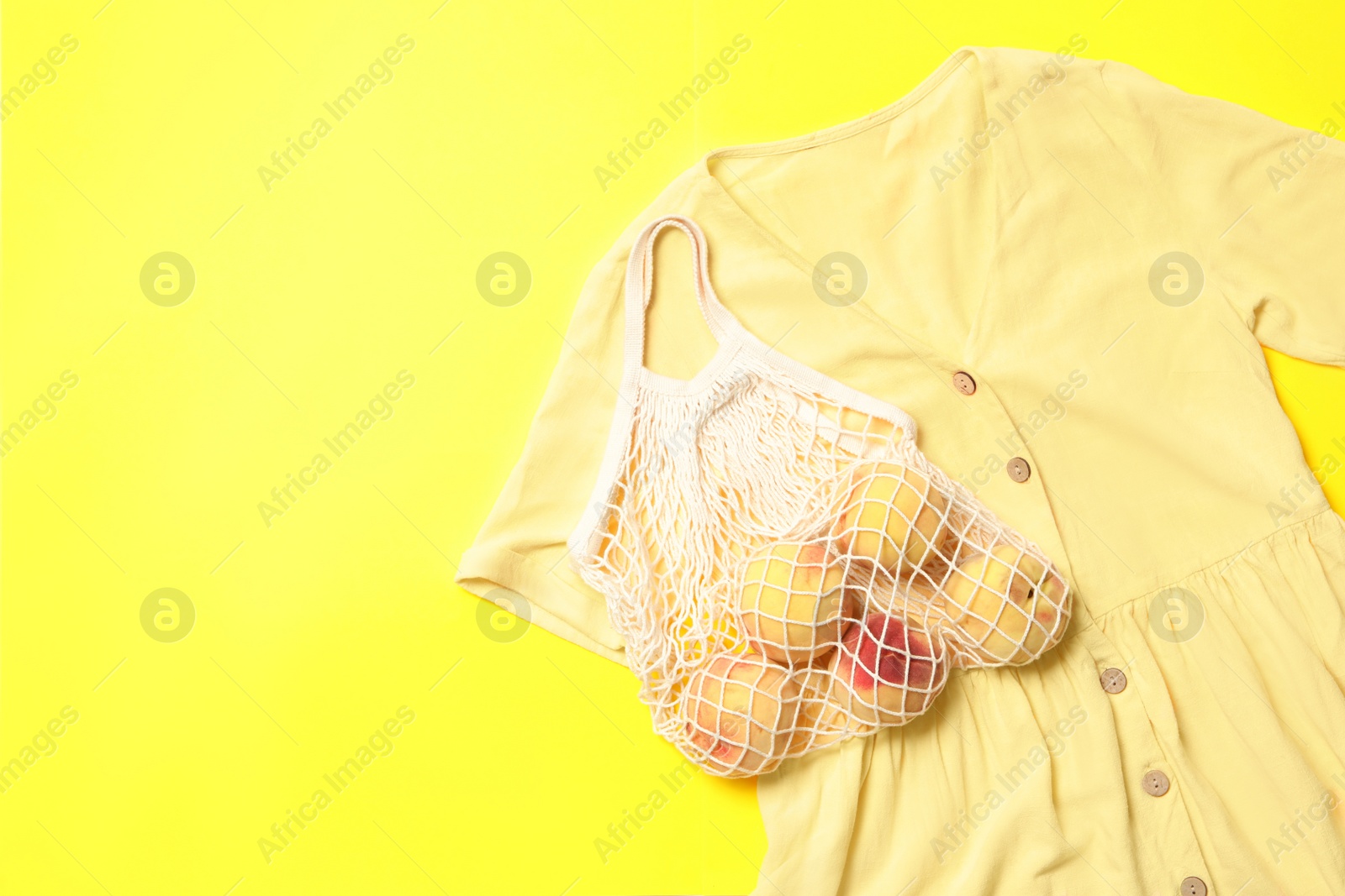 Photo of Stylish dress and peaches on yellow background, flat lay. Space for text