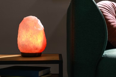 Himalayan salt lamp on wooden table indoors