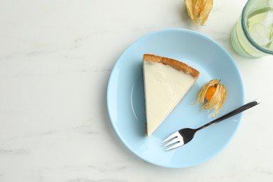 Photo of Piece of tasty vegan tofu cheesecake, fork and physalis fruit on white marble table, flat lay. Space for text