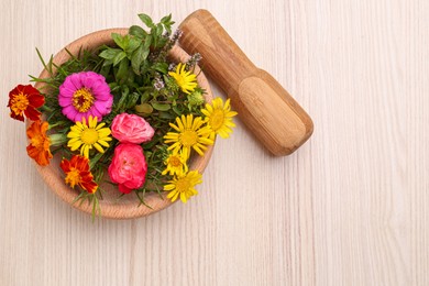 Photo of Mortar with pestle and beautiful fresh flowers on wooden table, top view. Space for text