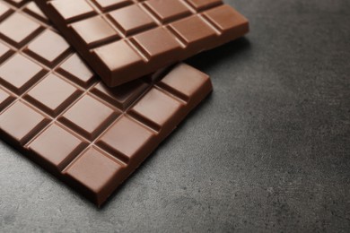 Photo of Delicious milk chocolate bars on black table, closeup. Space for text