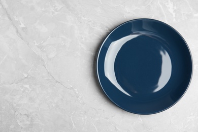 Photo of Empty blue ceramic plate on light grey marble table, top view. Space for text