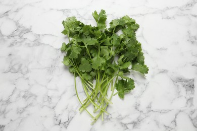 Photo of Bunch of fresh green cilantro on white marble table, top view