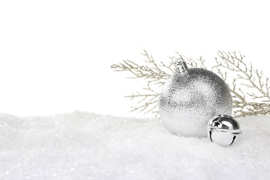 Photo of Beautiful silver Christmas ball, decorative branch and sleigh bell on snow against white background
