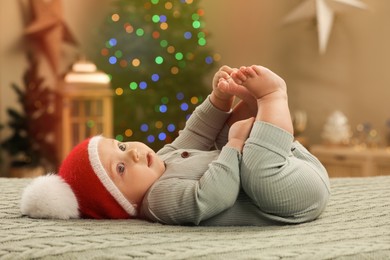 Cute little baby lying on knitted plaid in room decorated for Christmas. Winter holiday