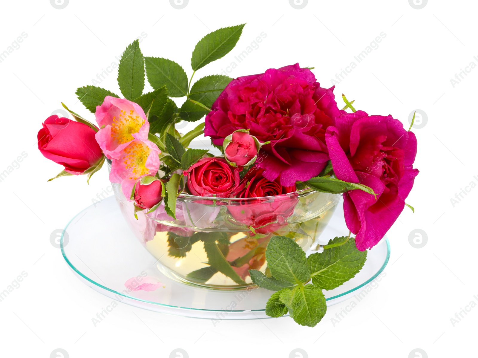 Photo of Aromatic herbal tea in glass cup with different flowers isolated on white