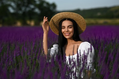 Photo of Beautiful young woman with straw hat in lavender field