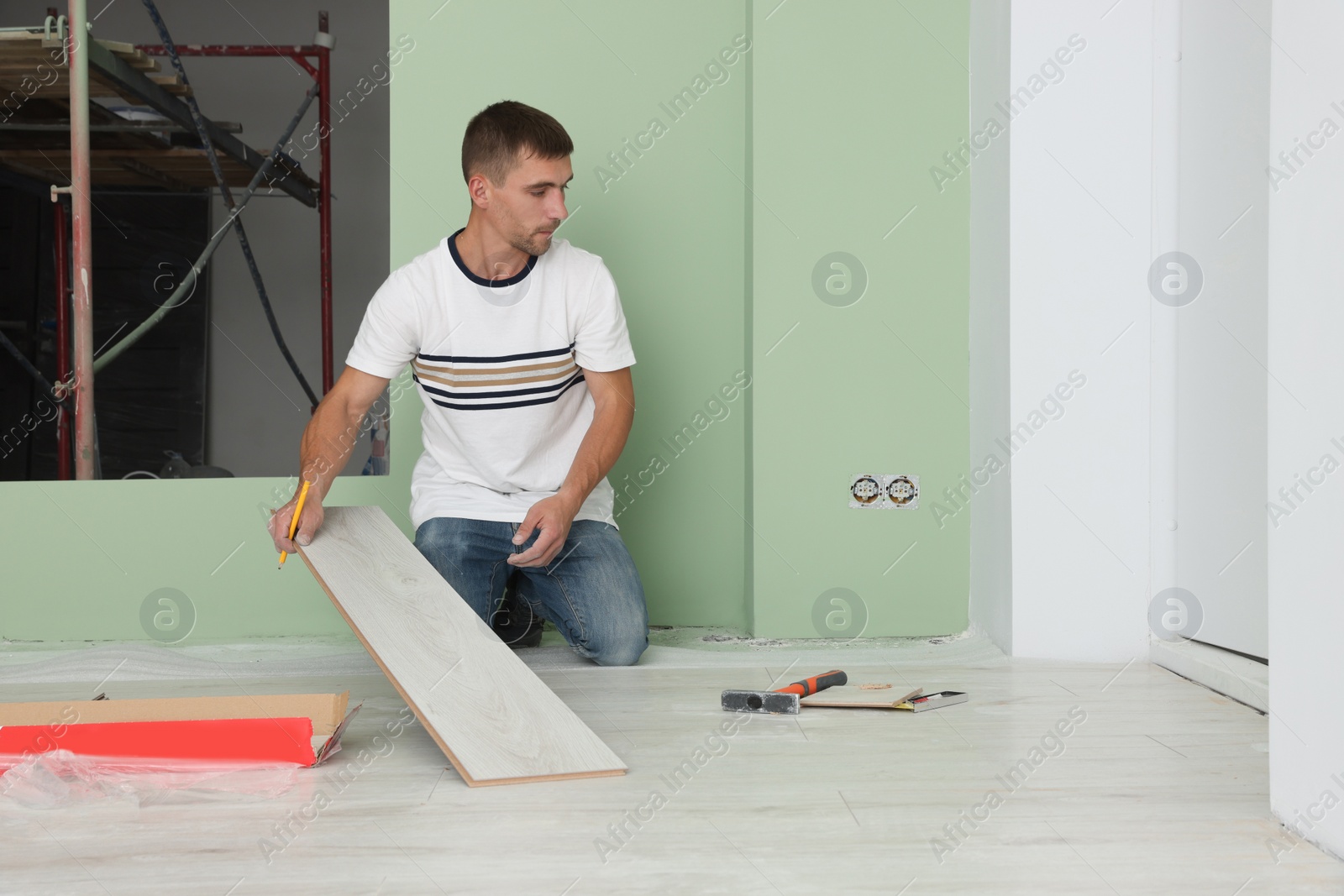 Photo of Man installing new laminate flooring in room