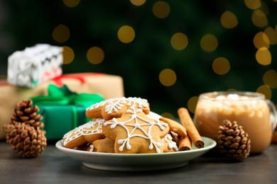 Decorated cookies and hot drink on grey table against blurred Christmas lights