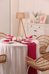 Color accent table setting. Plates, cutlery and pink napkins in dining room