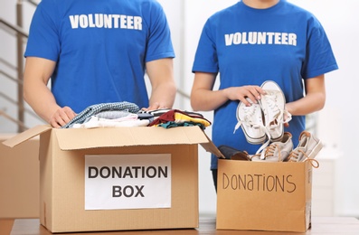 Volunteers putting clothes and shoes in donation boxes indoors