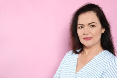 Portrait of mature woman with beautiful face on pink background. Space for text