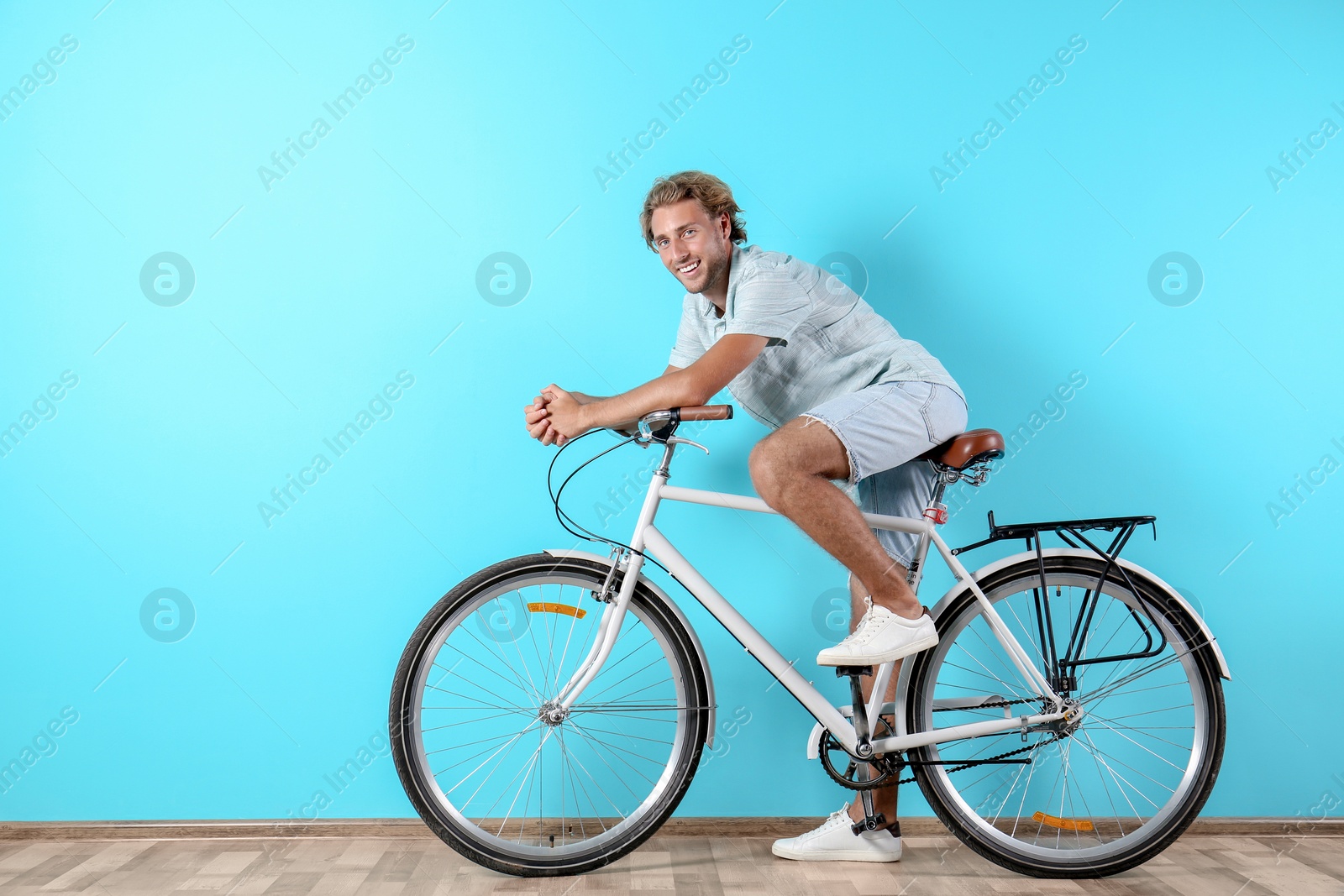 Photo of Handsome man with bicycle against color wall. Space for text