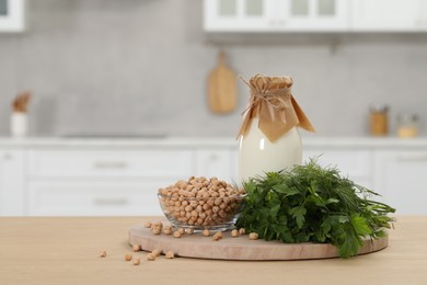 Photo of Bottle with milk, chickpeas and herbs on table in kitchen. Space for text