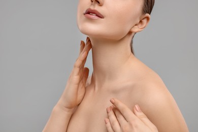 Photo of Woman touching her neck on grey background, closeup. Space for text