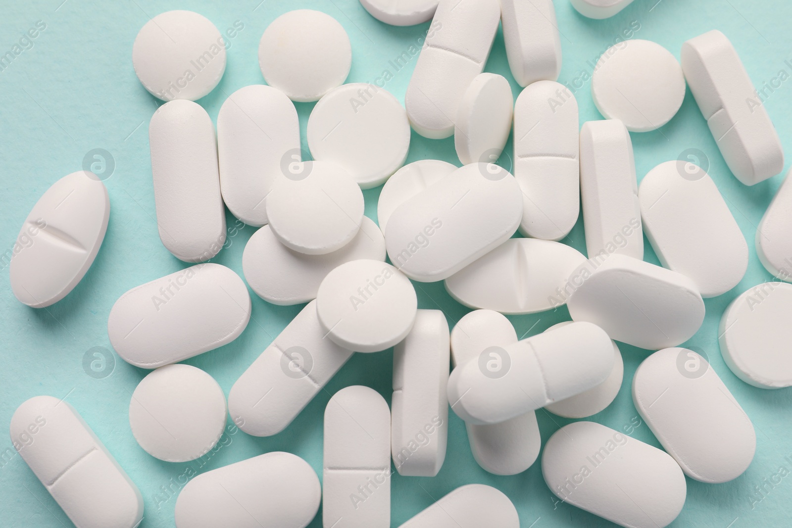 Photo of Many white pills on mint background, flat lay