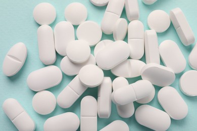 Photo of Many white pills on mint background, flat lay