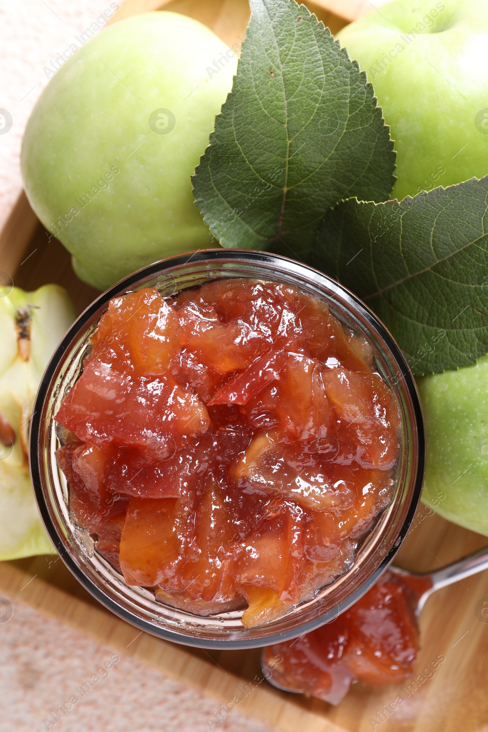 Photo of Glass jar of delicious apple jam and fresh fruits on light table, top view