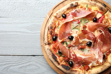 Tasty pizza with cured ham, olives and sun-dried tomato on gray wooden table, top view. Space for text