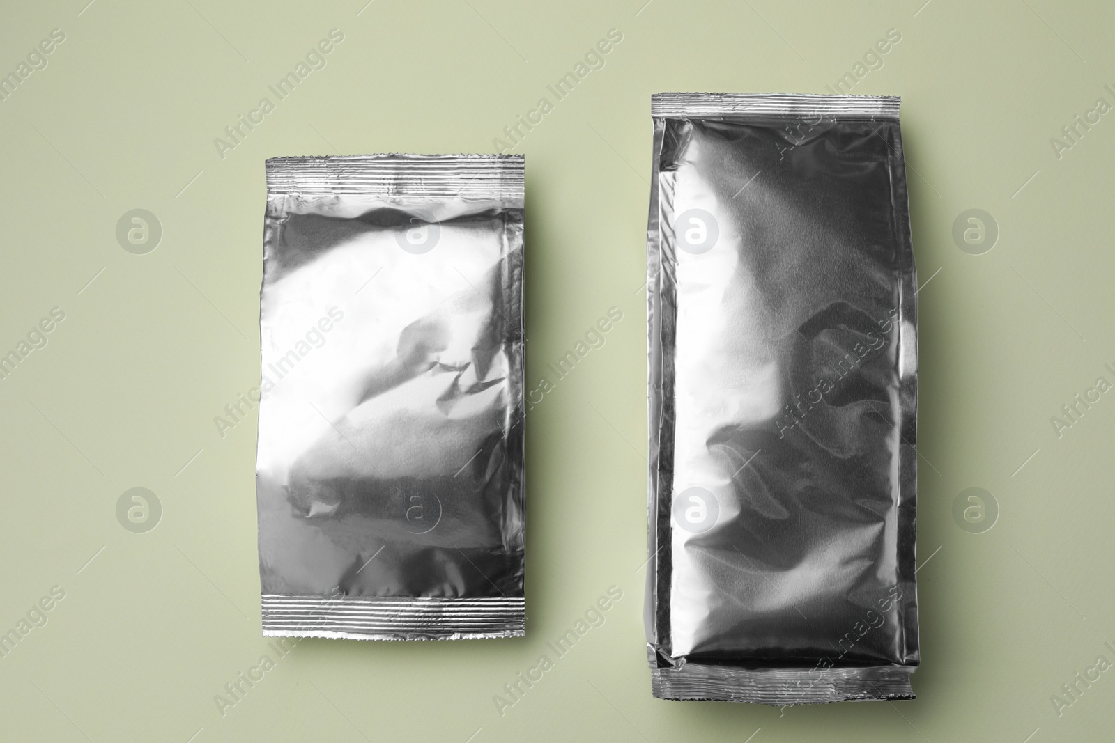 Photo of Blank foil packages on light background, flat lay