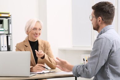 Photo of Happy woman having conversation with man at wooden table in office. Manager conducting job interview with applicant