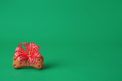 Photo of Bone shaped dog cookie with red bow on green background. Space for text