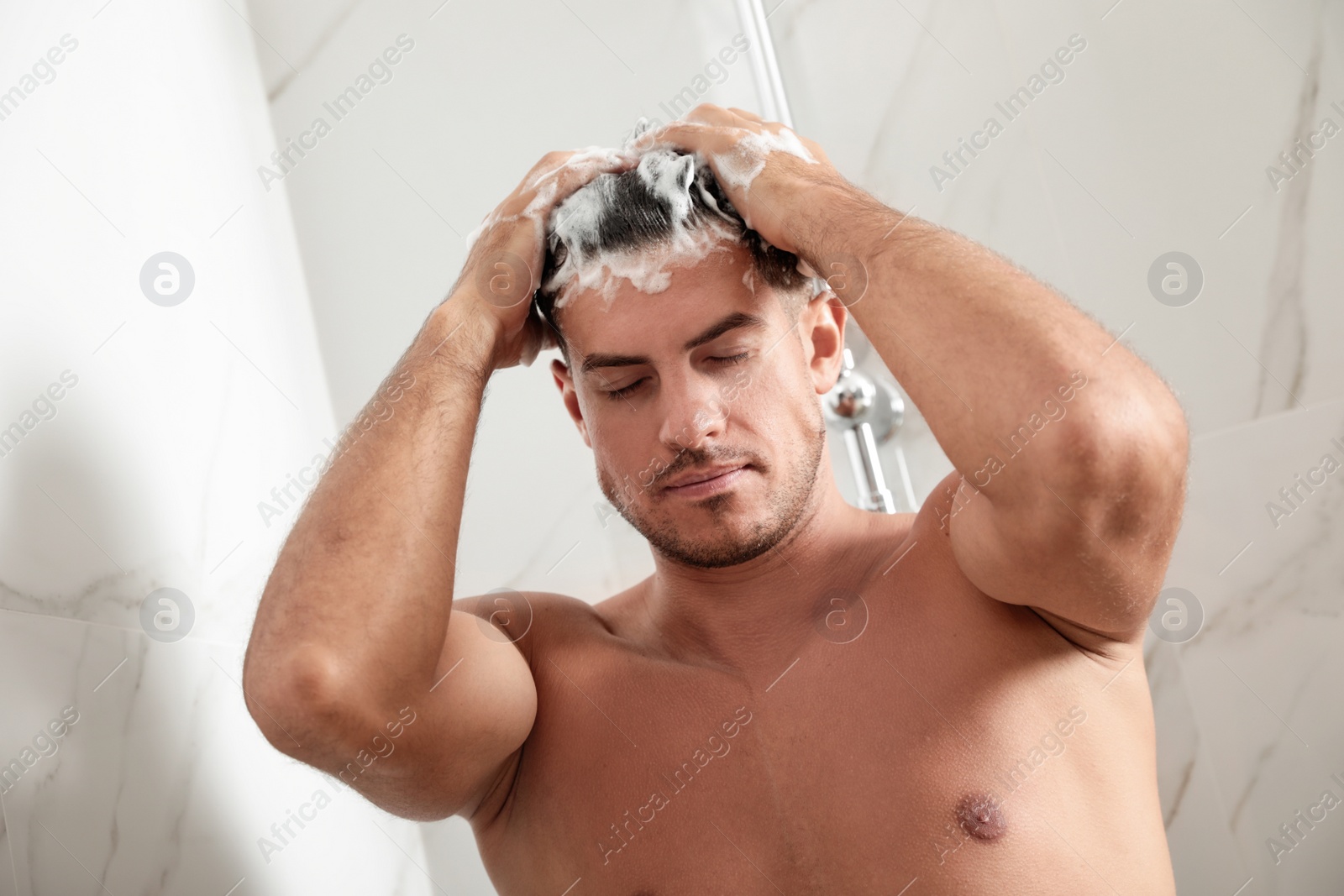 Photo of Handsome man washing hair in shower at home