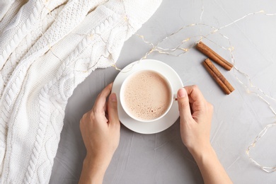 Woman with delicious hot cocoa drink at table, top view