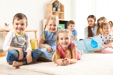 Photo of Playful little children resting on floor indoors