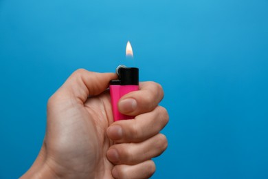 Photo of Woman holding pink lighter on light blue background, closeup