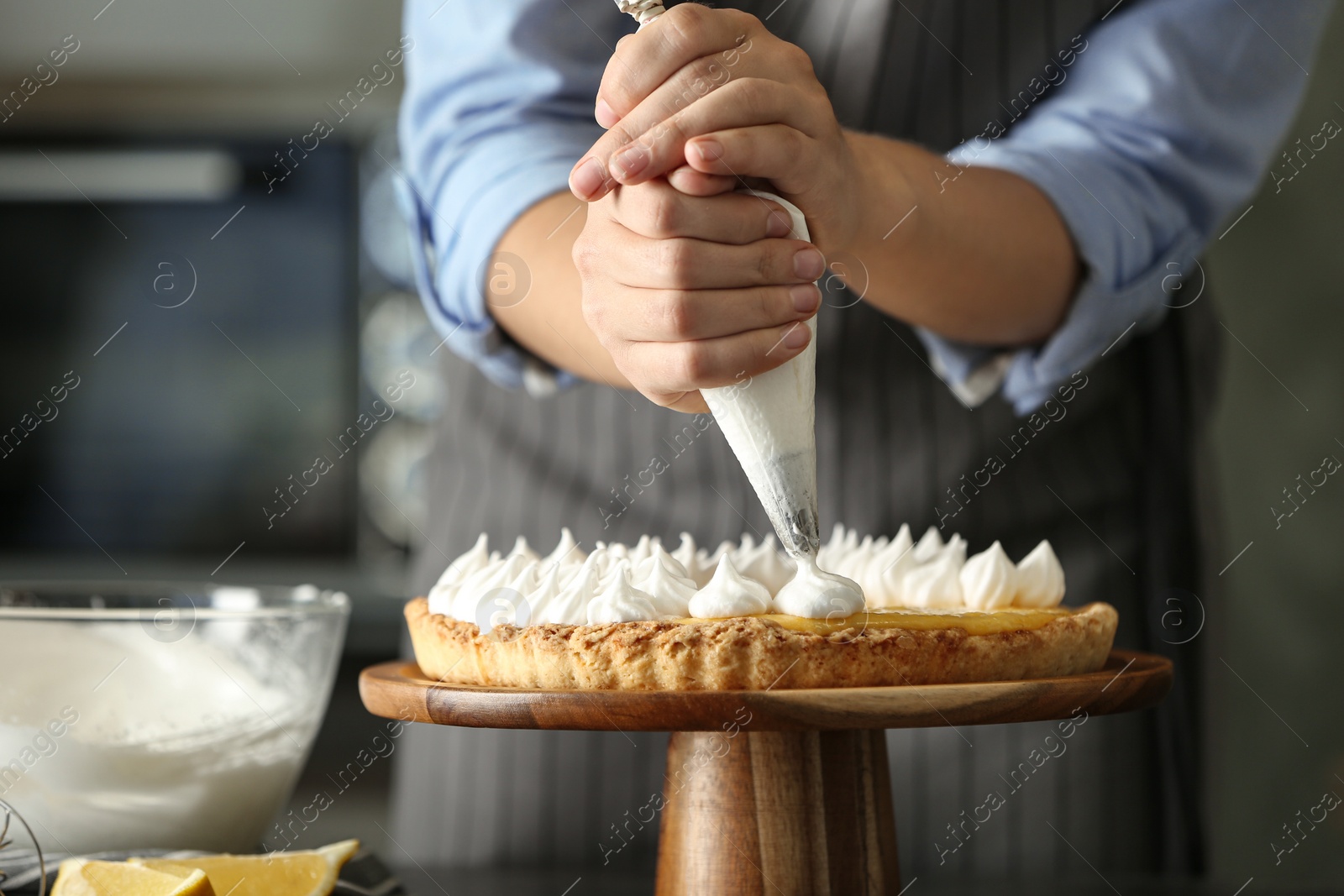 Photo of Woman preparing lemon meringue pie in kitchen, closeup