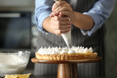 Photo of Woman preparing lemon meringue pie in kitchen, closeup